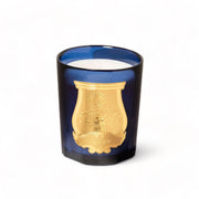 Image of Trudon's Salta classic 9.5 oz candle with dark blue glass, alabaster-white wax and gold foil label in the shape of a heraldic shield